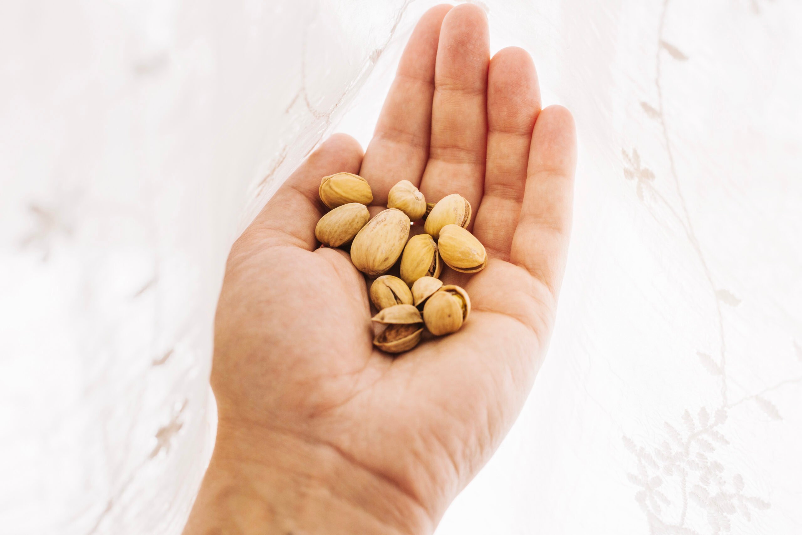 Hand holding a small pile of pistachios representing nuts and seeds rich in arginine